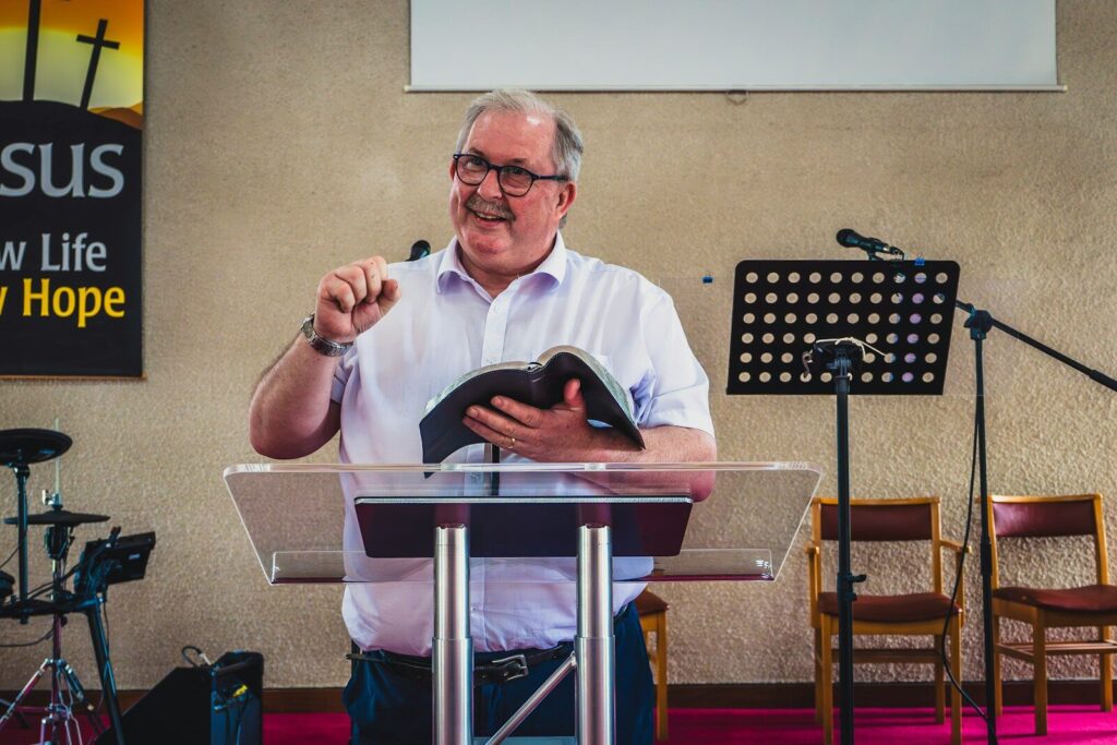 a man standing at a podium holding a book